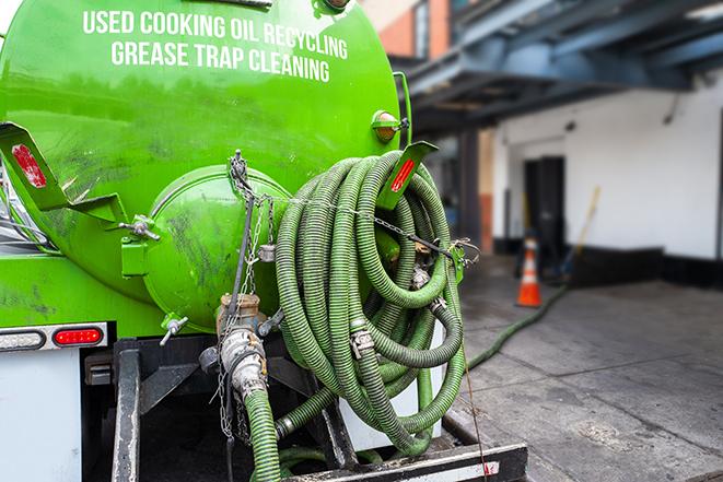 a professional plumber using a pump to empty a grease trap in Bayou Vista LA